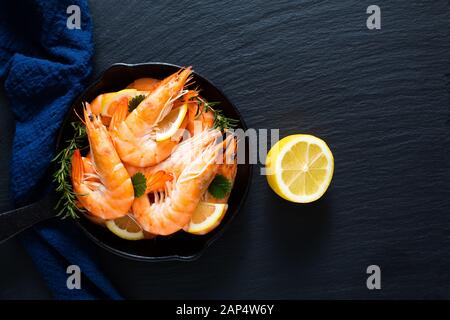 Seafood Concept Ocean King Garnelen in Eisenguss auf schwarzem Schieferstein mit blauen Servietten gekocht