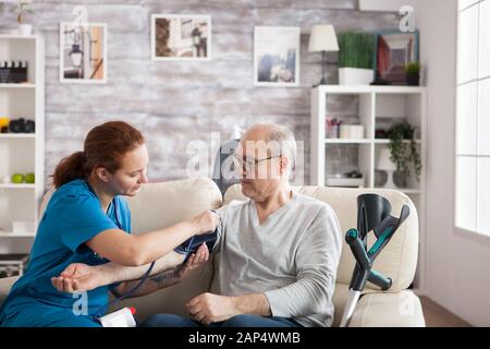 Die Krankenschwester, die ein digitales Gerät am Old-man-Arm anhängt, prüft den Blutdruck. Stockfoto