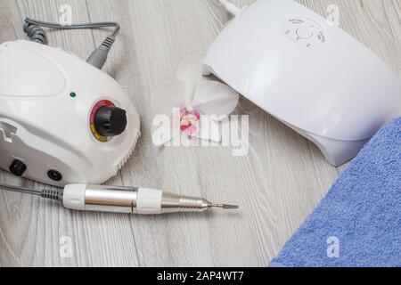 Fräser, LED-UV-Lampe und blauen Handtuch mit White Orchid Flower auf grau Holz- Hintergrund. Eine Reihe von kosmetischen Werkzeuge für professionelle Hardware manic Stockfoto