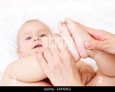 Masseur massiert kleines Baby Füße, flachen Fokus Stockfoto