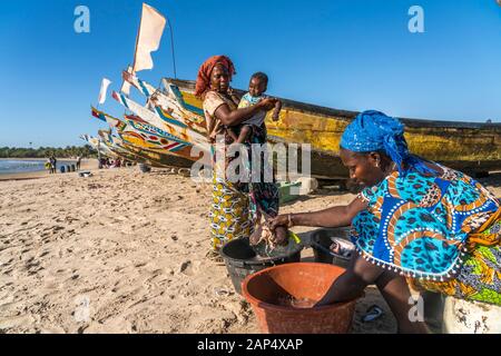 Die Frauen der Fischer mit den Fischerboote am Strand von Sanyang, Gambia, Westafrika | Fisherman's Frau mit ihren bunten Fischerboote bei t Stockfoto