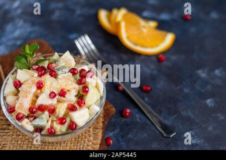 Diät Obstsalat zum Frühstück. Kiwi orange Banane und Apfel gewürfelt und gewürzt mit Joghurt mit Honig. Gesunde Ernährung, Vegetarismus. Auf einem dunklen backgro Stockfoto