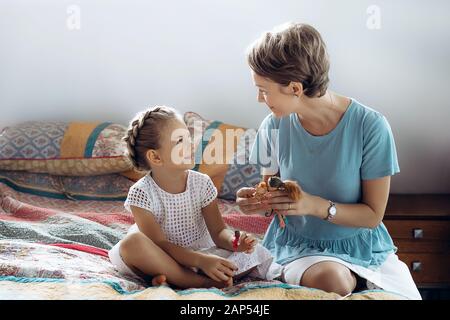 Mutter und ihre kleine Tochter sprechen auf dem Bett. Stockfoto