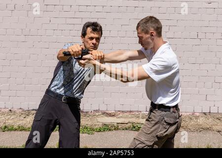 Verteidiger verteidigt sich mit einer Waffe gegen den Angreifer. Selbstverteidigungsmethoden Krav Maga Stockfoto