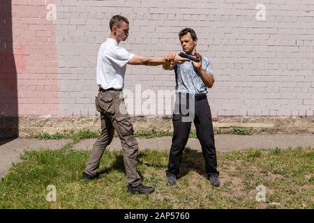 Verteidiger verteidigt sich mit einer Waffe gegen den Angreifer. Selbstverteidigungsmethoden Krav Maga Stockfoto