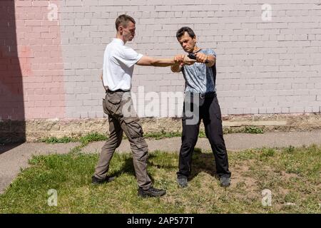 Verteidiger verteidigt sich mit einer Waffe gegen den Angreifer. Selbstverteidigungsmethoden Krav Maga Stockfoto