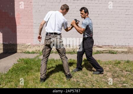 Verteidiger verteidigt sich mit einer Waffe gegen den Angreifer. Selbstverteidigungsmethoden Krav Maga Stockfoto