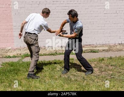 Verteidiger verteidigt sich mit einer Waffe gegen den Angreifer. Selbstverteidigungsmethoden Krav Maga Stockfoto