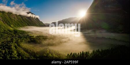 Morgennebel über dem Tal zwischen den Bergen im Sonnenlicht. Nebel und schöne Natur Norwegen Luftaufnahmen. Stockfoto