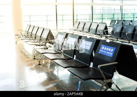 Leere Sitzplätze an einem Flughafen im Wartebereich vor dem Einsteigen. Blaue Schilder auf Stühlen Stockfoto