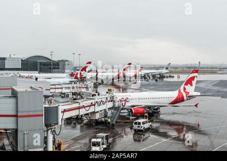 Luftbild der Flugzeuge der Air Canada an einem regnerischen Tag am Terminal, auf der Landebahn geparkt und bereit, Passagiere von der Jet-Brücke zu Bord zu bringen Stockfoto