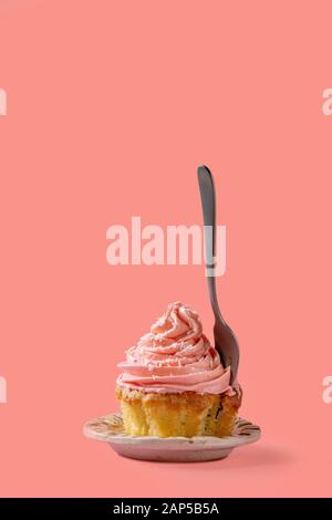 Hausgemachte Cupcake mit Rosa buttercream und Kokosraspeln, mit Dessert Gabel innerhalb von über rot rosa Hintergrund. Stockfoto