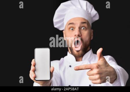 Küchenchef Zeigt Telefonbildschirm Empfehlung Auf Schwarzem Hintergrund, Mockup Stockfoto