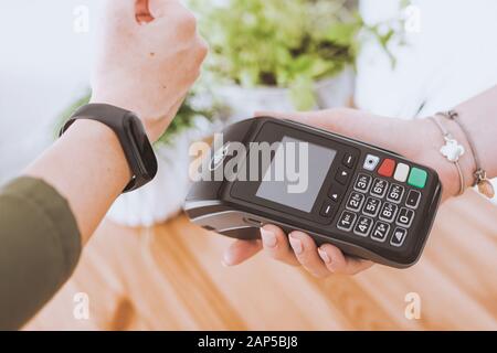 Frau verwendet Terminal für kontaktlose Zahlung per Smartwatch. Neue Technologie der NFC-Zahlung Stockfoto