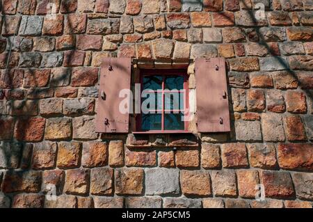 Rustikales, offenes Fenster in orangefarbenem historischem Steingewand an einem sonnigen Tag Stockfoto