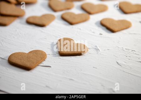 Leckere Herzen Cookies auf einem weißen Hintergrund. Selbstgemachte Plätzchen auf einem Stock in der Form der Herzen auf einen hölzernen Tisch. Cookies mit Herz zu Valentin Stockfoto