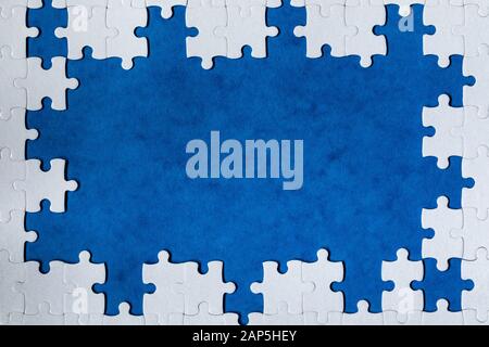 Framing in Form eines Rechtecks, einer weissen Puzzle gemacht. Frame Text und Puzzles. Rahmen aus Puzzle Stücke auf Blau backgroun Stockfoto