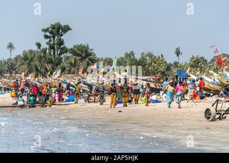 Die Frauen der Fischer mit den Fischerboote am Strand von Sanyang, Gambia, Westafrika | Fisherman's Frau mit ihren bunten Fischerboote bei t Stockfoto