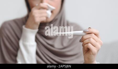 Thermometer in den Händen einer nicht erkennbaren kranken muslimin in Hijab Stockfoto