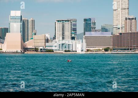 HongKong, China - November, 2019: Kleines Boot im Victoria Hafen mit Skyline und Küste Aussicht auf Hong Kong, Kowloon, Tsim Sha Tsui Stockfoto