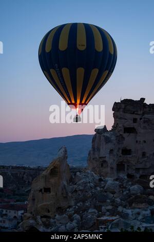 Kappadokien, Türkei: Heißluftballon im Morgengrauen auf der Kirche St. Johannes der Täufer (Burg Cavusin), berühmte Höhlenkirche aus dem 5. Jahrhundert auf dem Hügel Stockfoto