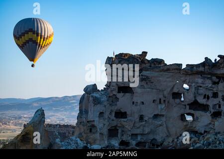 Kappadokien, Türkei: Heißluftballon im Morgengrauen auf der Kirche St. Johannes der Täufer (Burg Cavusin), berühmte Höhlenkirche aus dem 5. Jahrhundert auf dem Hügel Stockfoto