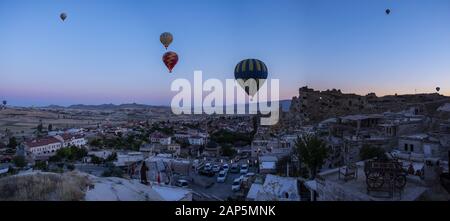 Kappadokien, Türkei: Heißluftballons im Morgengrauen auf der Kirche St. Johannes der Täufer (Burg Cavusin), berühmte Höhlenkirche aus dem 5. Jahrhundert auf dem Hügel Stockfoto