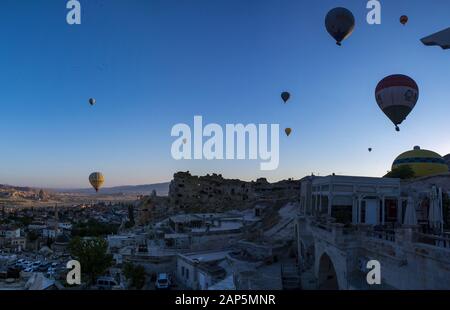 Kappadokien, Türkei: Heißluftballons im Morgengrauen auf der Kirche St. Johannes der Täufer (Burg Cavusin), berühmte Höhlenkirche aus dem 5. Jahrhundert auf dem Hügel Stockfoto