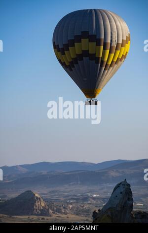 Kappadokien, Türkei: Heißluftballon im Morgengrauen auf der Kirche St. Johannes der Täufer (Burg Cavusin), berühmte Höhlenkirche aus dem 5. Jahrhundert auf dem Hügel Stockfoto