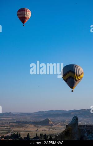 Kappadokien, Türkei: Heißluftballons im Morgengrauen auf der Kirche St. Johannes der Täufer (Burg Cavusin), berühmte Höhlenkirche aus dem 5. Jahrhundert auf dem Hügel Stockfoto