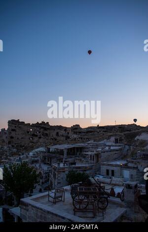 Kappadokien, Türkei: Heißluftballons im Morgengrauen auf der Kirche St. Johannes der Täufer (Burg Cavusin), berühmte Höhlenkirche aus dem 5. Jahrhundert auf dem Hügel Stockfoto