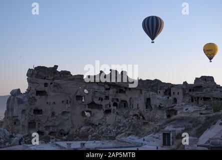 Kappadokien, Türkei: Heißluftballons im Morgengrauen auf der Kirche St. Johannes der Täufer (Burg Cavusin), berühmte Höhlenkirche aus dem 5. Jahrhundert auf dem Hügel Stockfoto