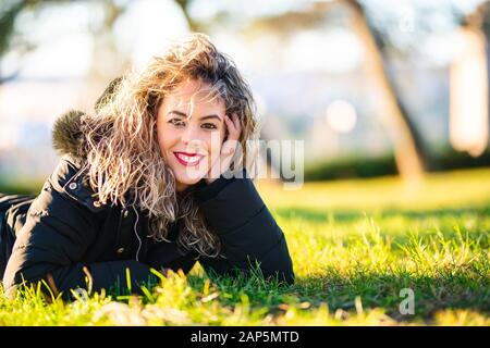 Junge hübsche Frau mit Mantel auf dem Gras Stockfoto