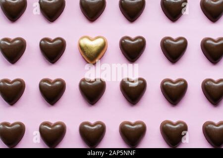 Flat Lay mit Schokoladenherzen mit einer gelben Goldbonbons, die aufstehen, Stockfoto