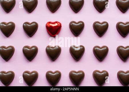 Flat Lay mit Schokoladenherzen mit einer Süßigkeit in einer roten Folie, die aufsteht, Stockfoto