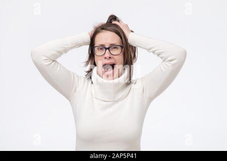 Junge kaukasier Frau in Gläser mit entsetzten Gesichtsausdruck mit Neuigkeiten überrascht wird. Studio shot Stockfoto