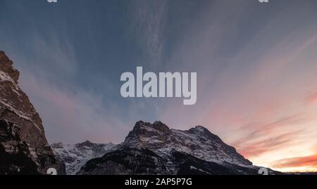 Die Sonne geht über den Eiger und andere Berge rund um das Alpendorf Grindelwald, Schweiz. Stockfoto