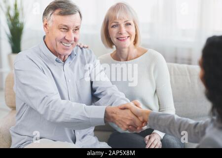 Glückliches reifes Paar, das dem Arzt einen Handschlag gibt Stockfoto