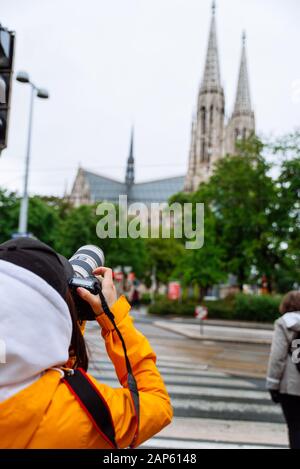 Frau mit professioneller Kamera, die sich ein Bild von der alten gotischen Kirche machen kann Stockfoto