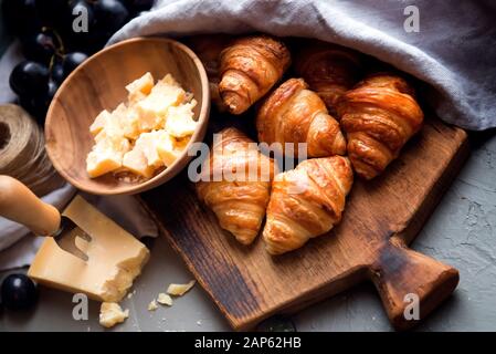 Originelle, leckere französische Croissants mit Käse und Trauben auf dem Holztisch. Butterig flockige Viennoiserie Brötchen markante Halbmond Form. Käse Stockfoto