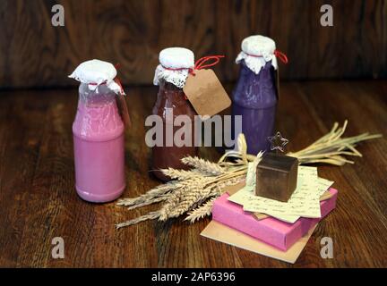 Bunte Smoothies an den Flaschen. Buntes Getränk, Milchshake in der Flasche mit frischem Gemüse und Superfoods auf Holzgrund. Gesund, sauber Stockfoto