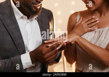 Schwarzer Mann setzt Ring auf den Finger seiner Frau Stockfoto