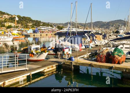Die Leute, die an einem sonnigen Tag auf einem Anlegeplatz am Hafen, Porto Maurizio, Imperia, Ligurien, Italien, warten, Fisch direkt von einem Fischer zu kaufen Stockfoto