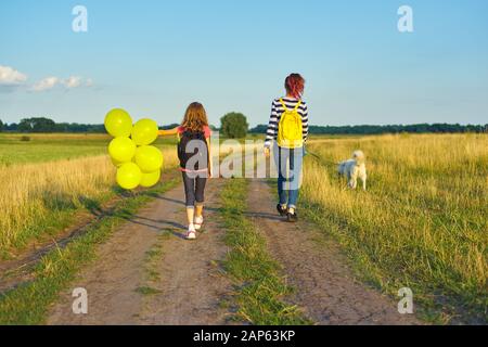 Kinder zwei Mädchen auf der Landstraße mit Hund und Ballon, Rückblick Stockfoto