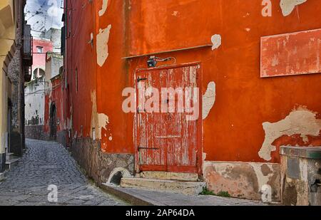 Die alte rote Tür und ihre Umgebung haben ihren eigenen Charme - Procida, Italien. Stockfoto