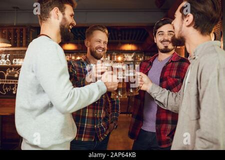 Gruppe der glücklichen Freunde klirren Gläser mit Bier in einer Sports Bar. Stockfoto