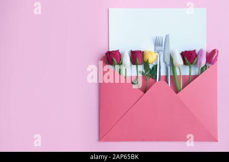 Umschlag mit verschiedenen Rosen und Tulpen und Messer und Gabel in der Mitte mit leerem Blatt Papier Stockfoto
