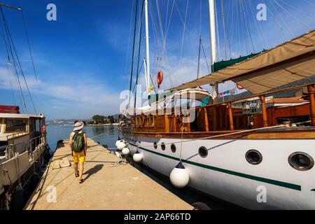 Angedockt Schiff im Hafen. Andocken an der Pier im Mittelmeer. Yachtcharter am Dock geparkt. Tourist mit Rucksack zu Fuß auf der Pier. Stockfoto