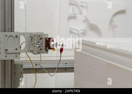 Kleine private Produktion zum Ausschneiden von Produkten und Figuren aus Schaumstoff an einer Maschine mit elektrischer Heizung. Herstellung von Isolierungen für Rohre Stockfoto