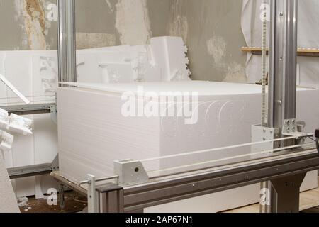 Kleine private Produktion zum Ausschneiden von Produkten und Figuren aus Schaumstoff an einer Maschine mit elektrischer Heizung. Herstellung von Isolierungen für Rohre Stockfoto